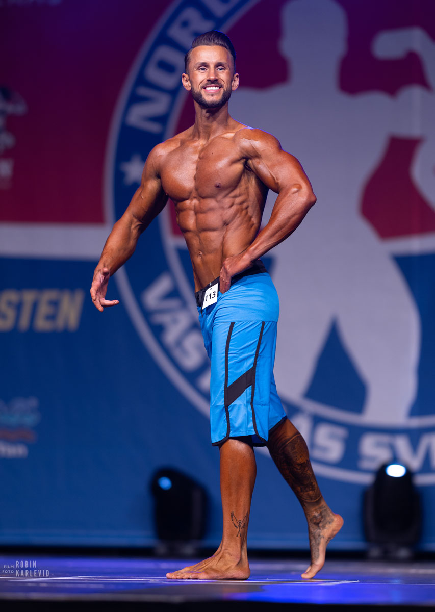 Tränaren poserar på bodybuildingmässan